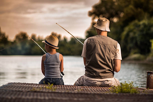 Rear view of a father and son fishing from the pier.
